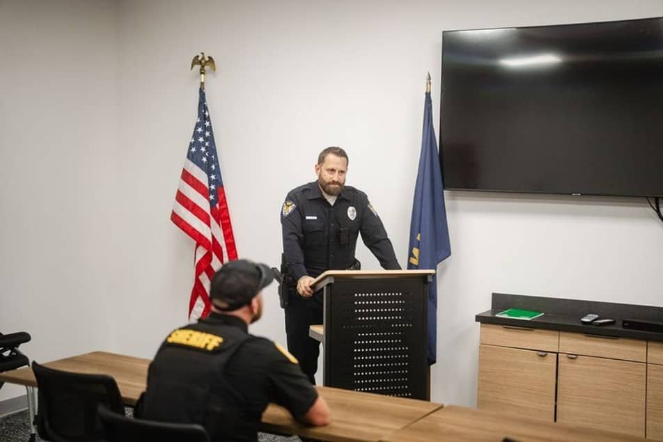 Police officer speaking at a podium in front of a class